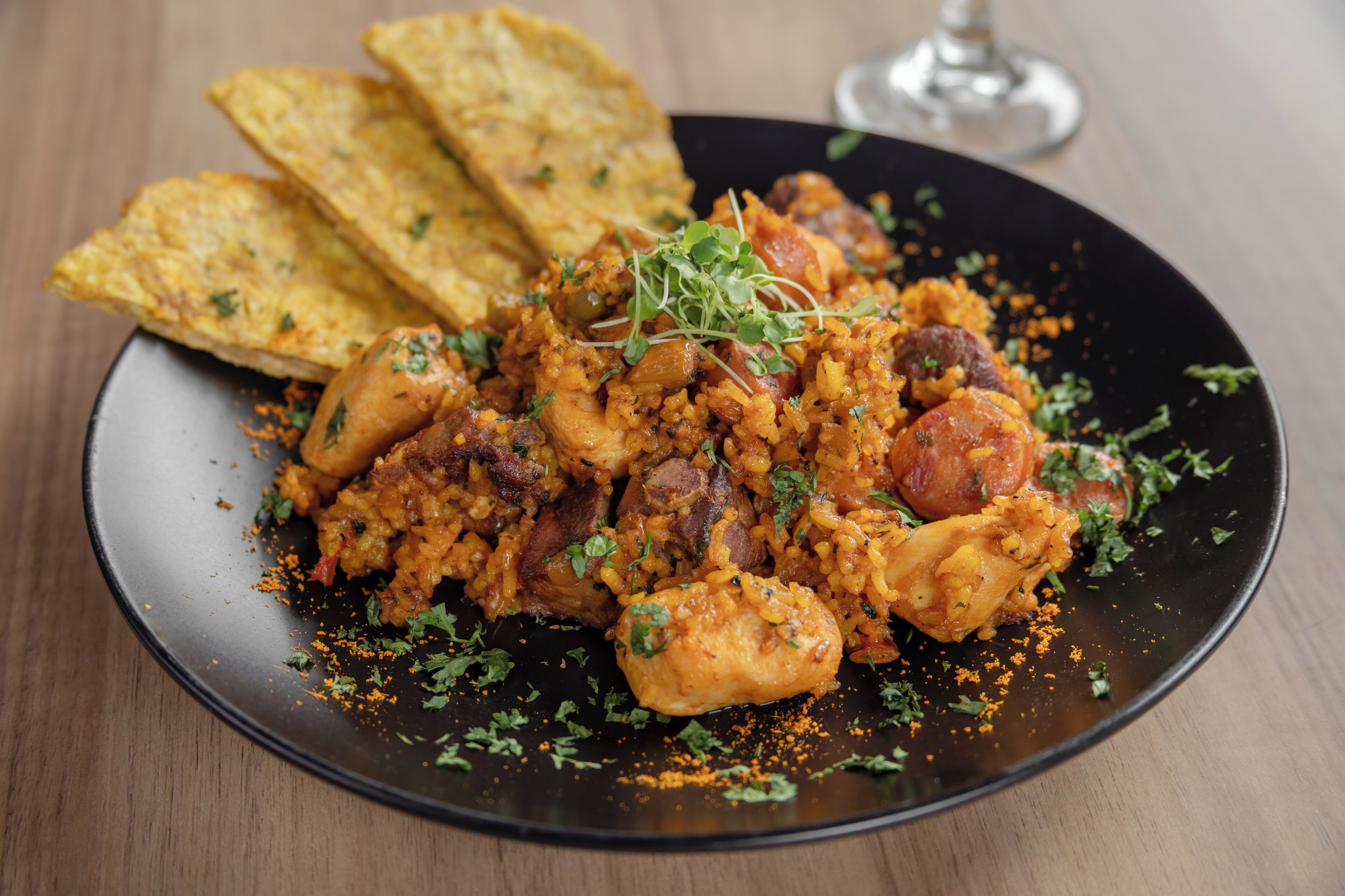 A plate of food with rice, meat, and garnishes, accompanied by tortilla chips.