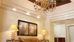 Um hall amplo com teto alto, um lustre, um sofá de couro marrom e duas luminárias.