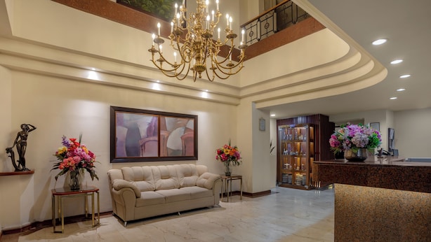 Um hall amplo com um sofá bege, um candelabro e um balcão de recepção.