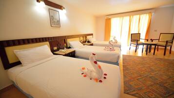 Habitación de hotel con dos camas, zona de comedor con sillas y alfombra estampada.