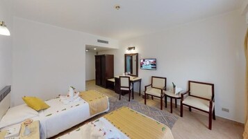 A hotel room with two beds, a desk, a chair, and a television.