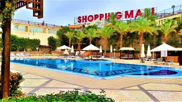 Een buitenzwembad, ligstoelen bij het zwembad