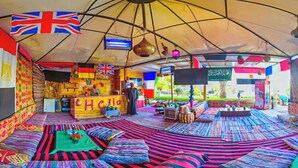 Un espacio con carpas, asientos de colores, una barra y banderas.