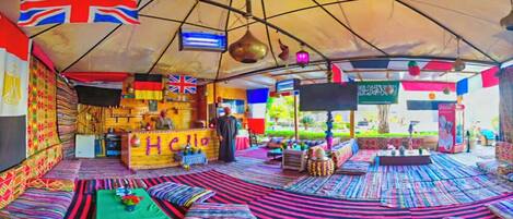 Un espacio con carpas, asientos de colores, una barra y banderas.