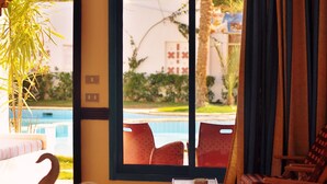 Habitación de hotel con cama, decoración de cisne, ventana con vista a una piscina y sillas exteriores.