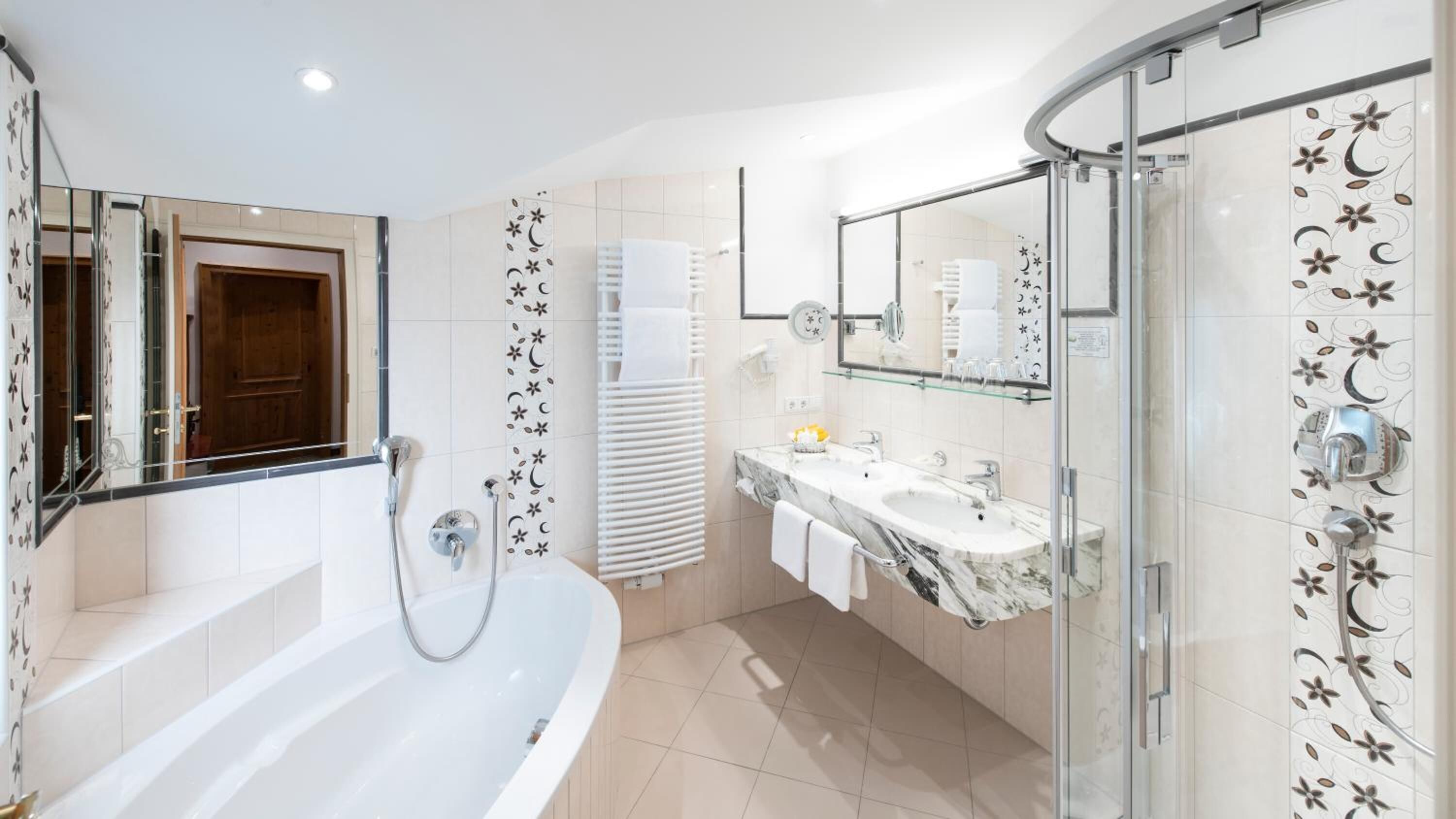Un baño moderno con una bañera independiente, una ducha con mampara de vidrio y un tocador con espejo.