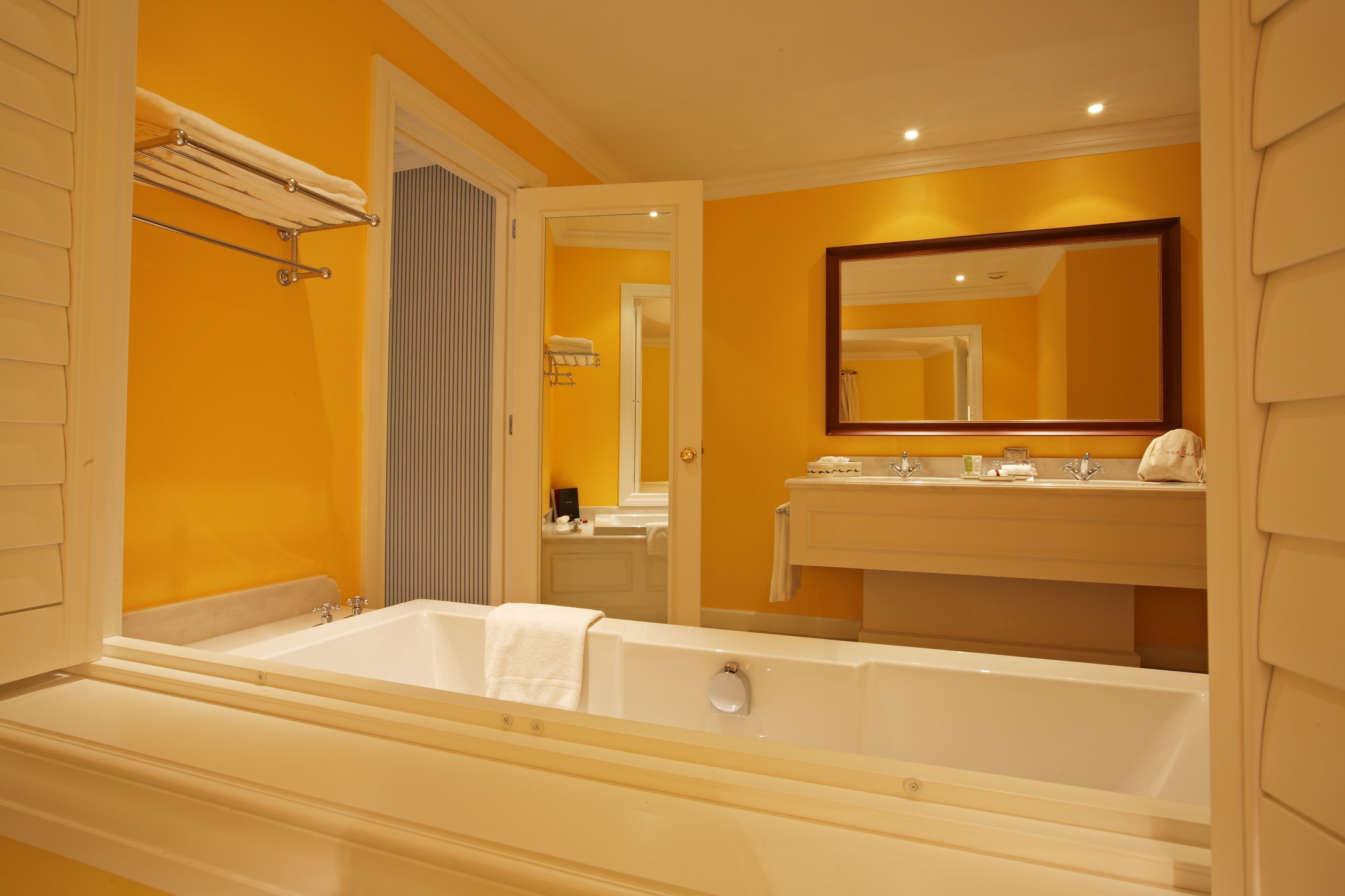 Un baño con una bañera grande, un espejo y un lavamanos con toallero.