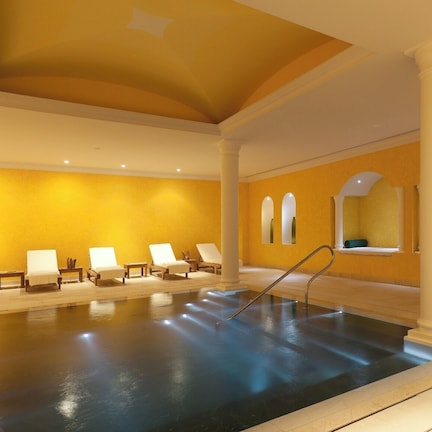 A spa area with a pool, sun loungers, and a ceiling with a curved design.