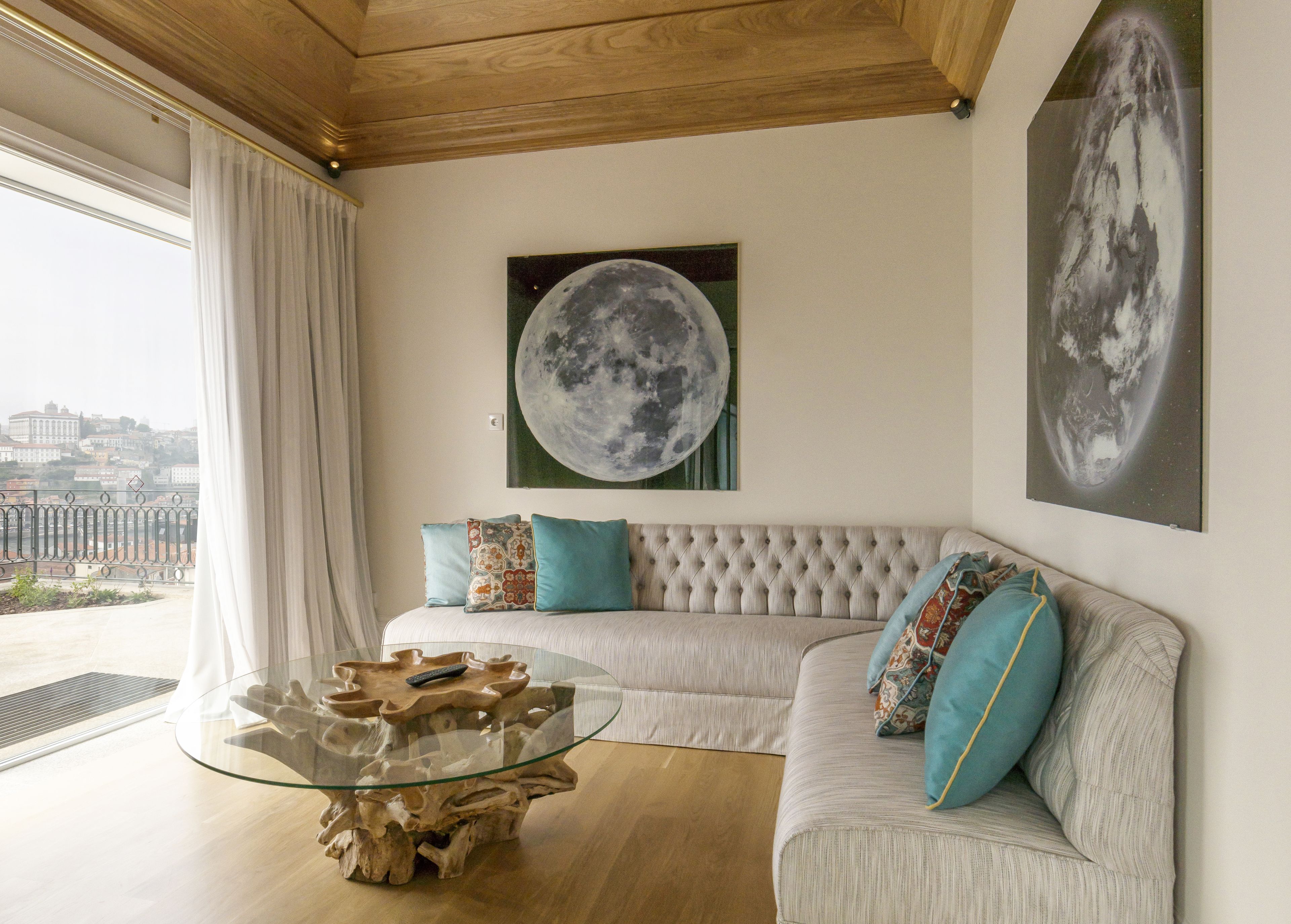 Ein Wohnzimmer mit einem Glastisch, einem gepolsterten Sofa und zwei großen Mondgemälden an der Wand.