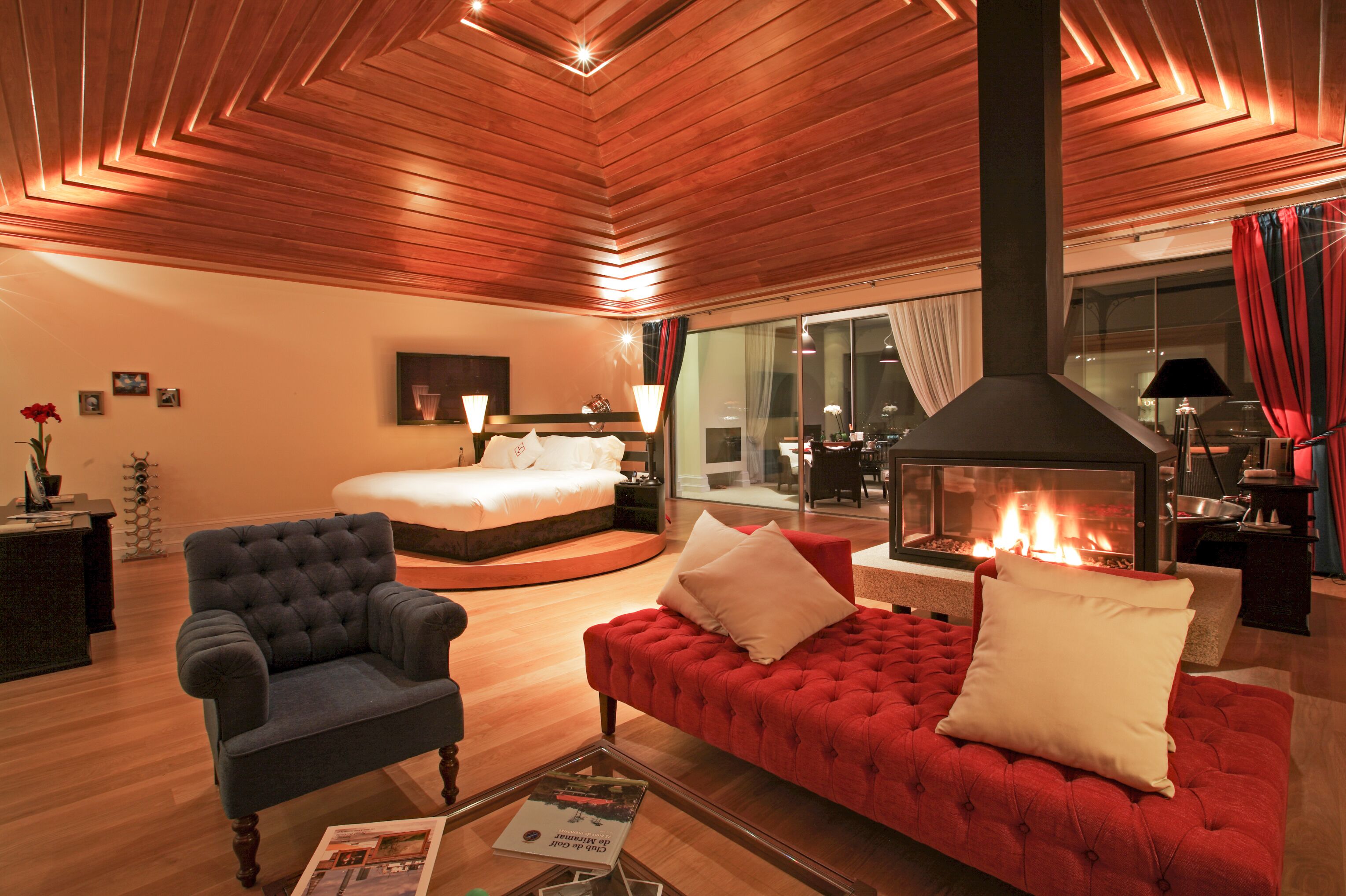 A modern living room with a fireplace, a sofa, a chair, and a bed.
