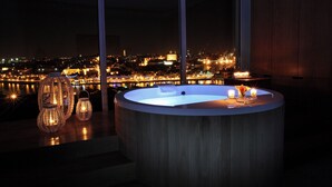 Un jacuzzi con vista a la ciudad, sillas de mimbre y velas.
