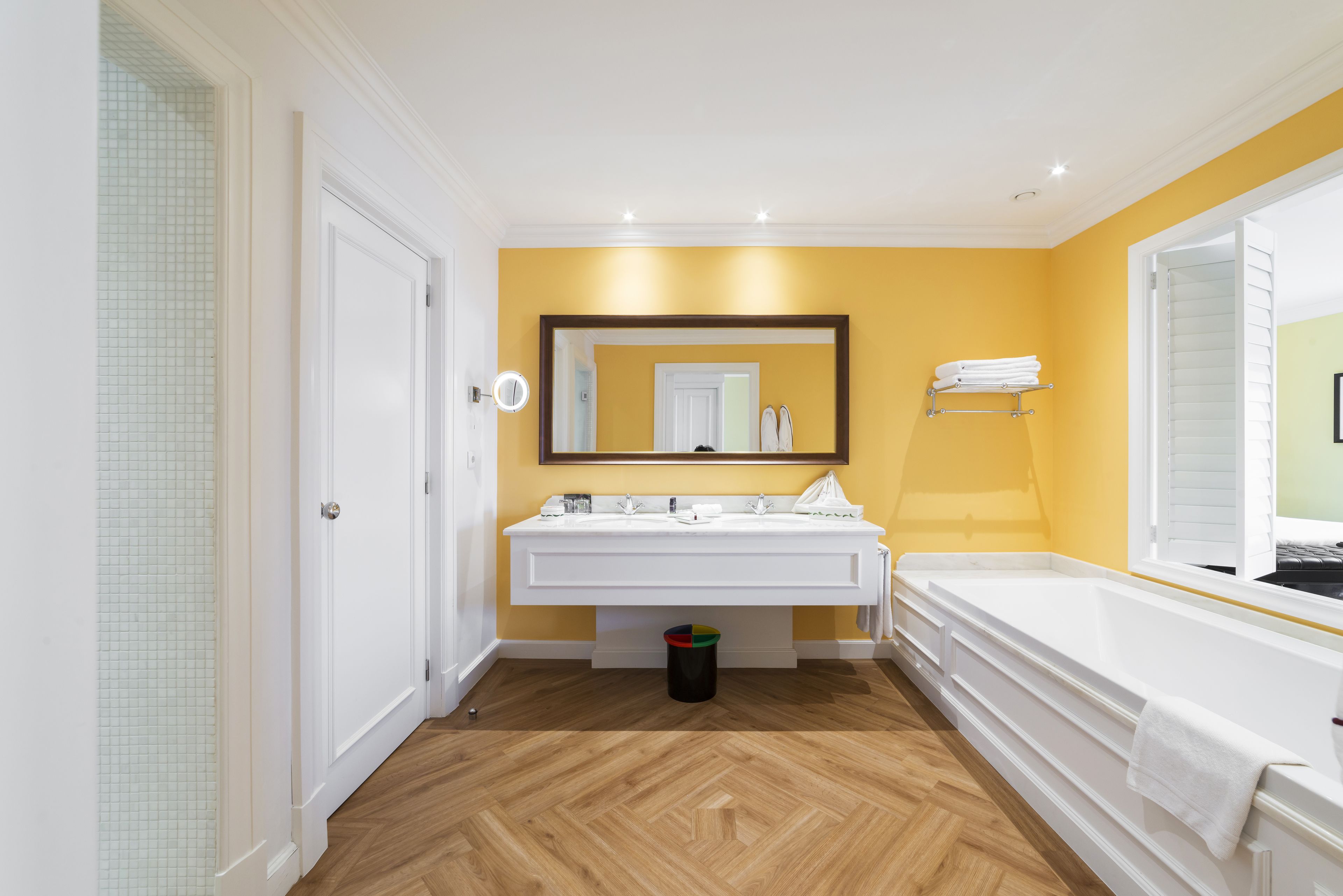 A bathroom with two sinks, a mirror, a bathtub, and a window.