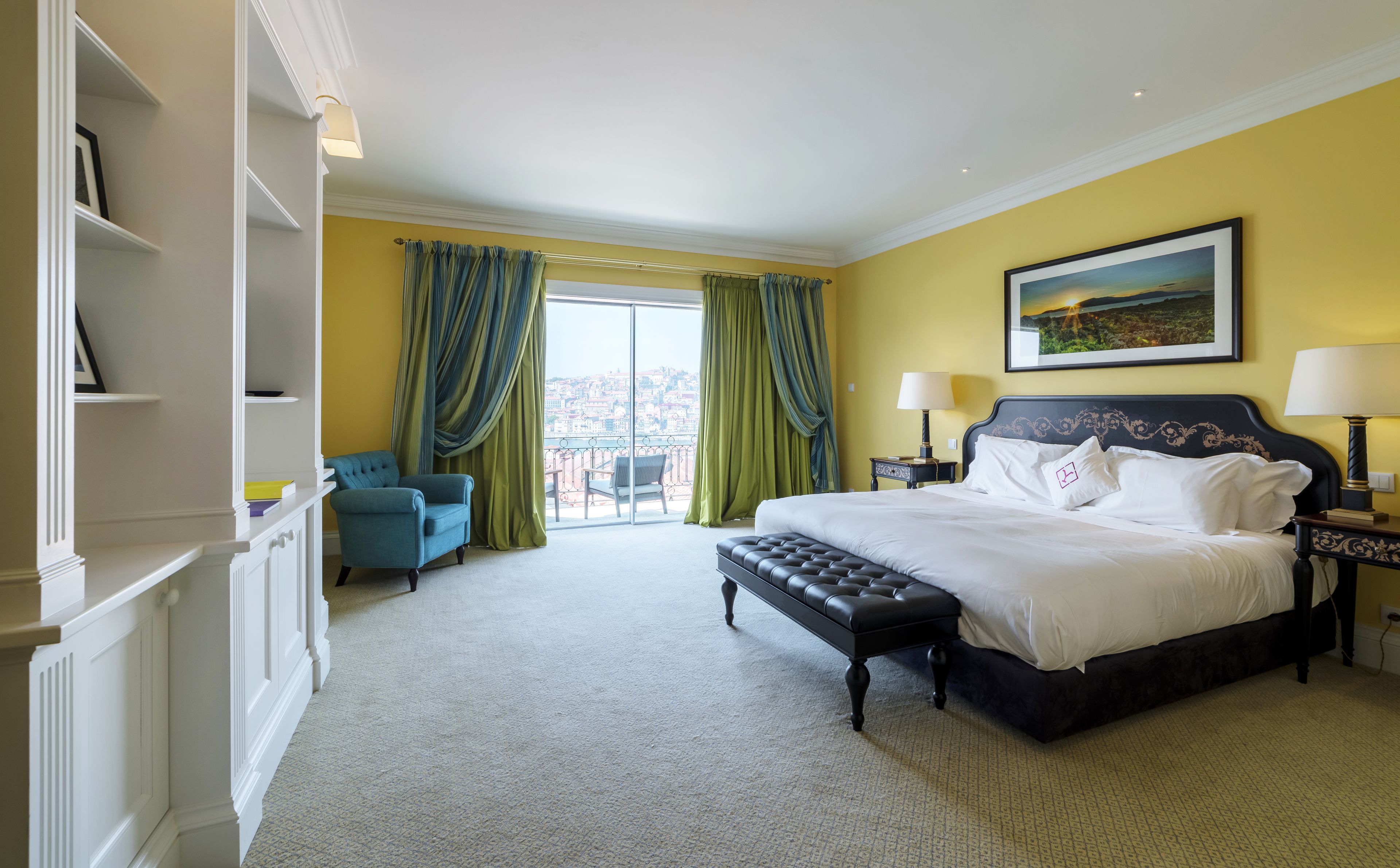 Habitación de hotel con una cama grande, una silla, un escritorio y vista a la ciudad por la ventana.