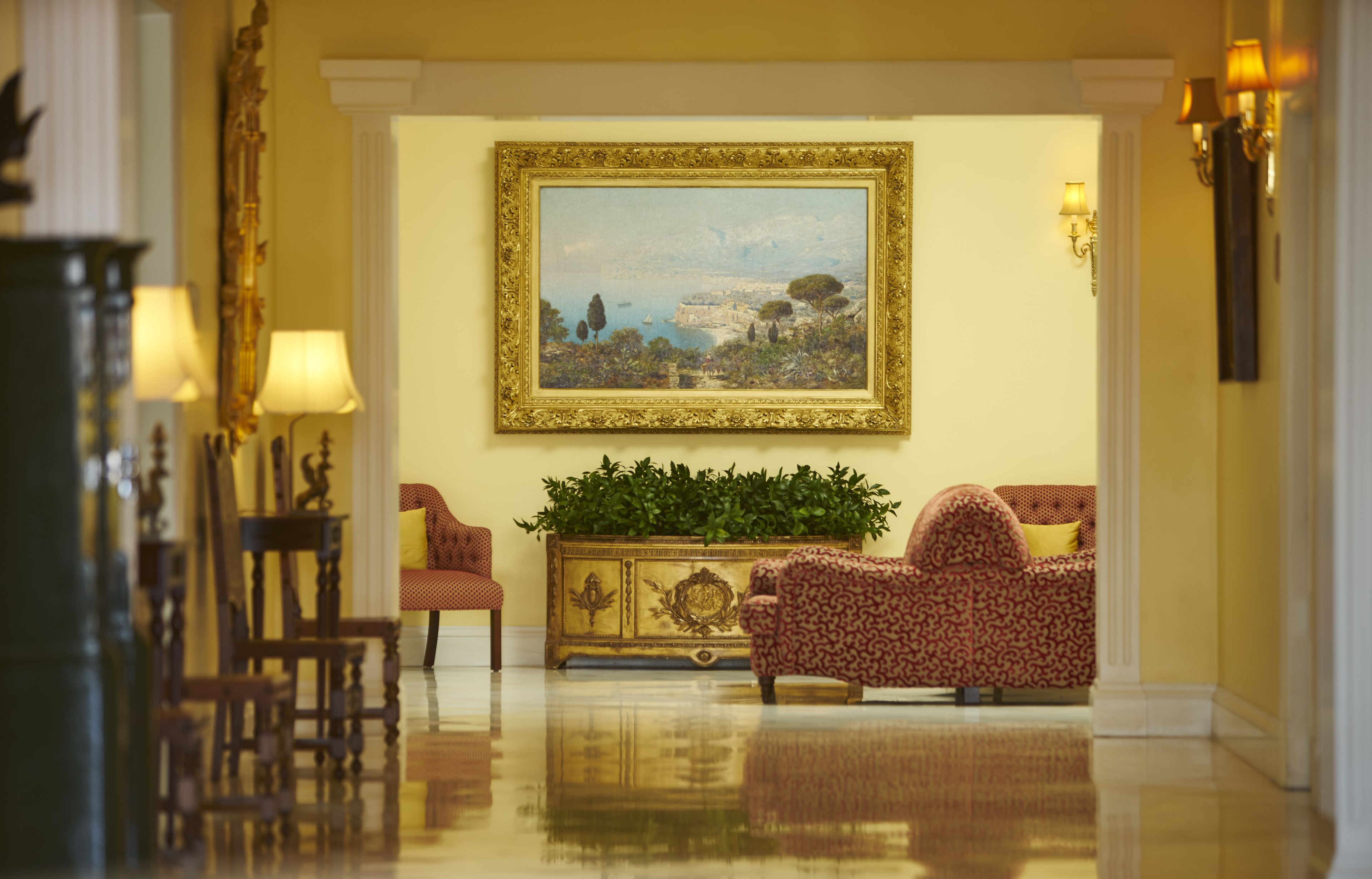 Un vestíbulo lujoso con un cuadro grande enmarcado, muebles elegantes y un piso reflectante.