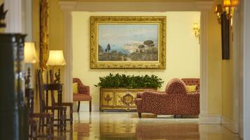 Un vestíbulo lujoso con un cuadro grande enmarcado, muebles elegantes y un piso reflectante.