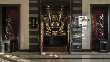 A modern hotel lobby with a central staircase, decorative wall panels, and a reception desk.