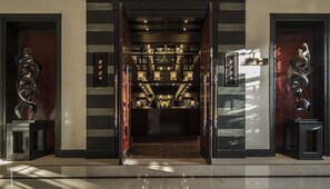 Un moderno vestíbulo de hotel con una escalera central, paneles decorativos en la pared y un mostrador de recepción.