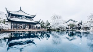 A traditional Chinese building with a reflection in a clear pool.
