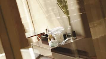 Ein Badezimmer mit einer Glasablage, auf der Toilettenartikel und eine Vase mit Blumen stehen.