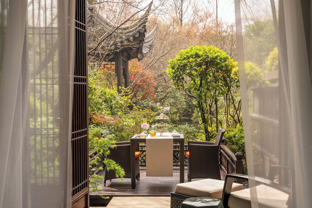 A traditional Chinese pavilion with a table and chairs in a garden setting.