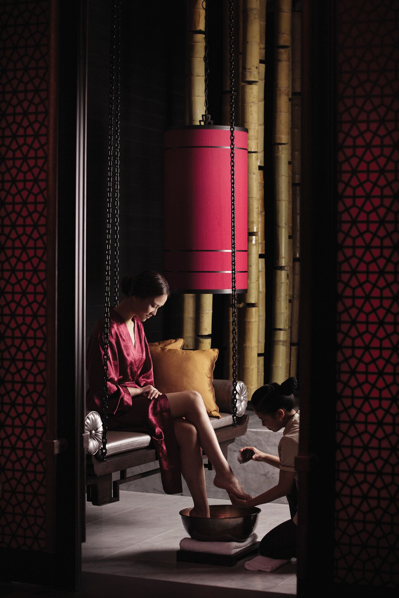 A room with a massage chair, a large red hanging massager, and a person receiving a foot massage.