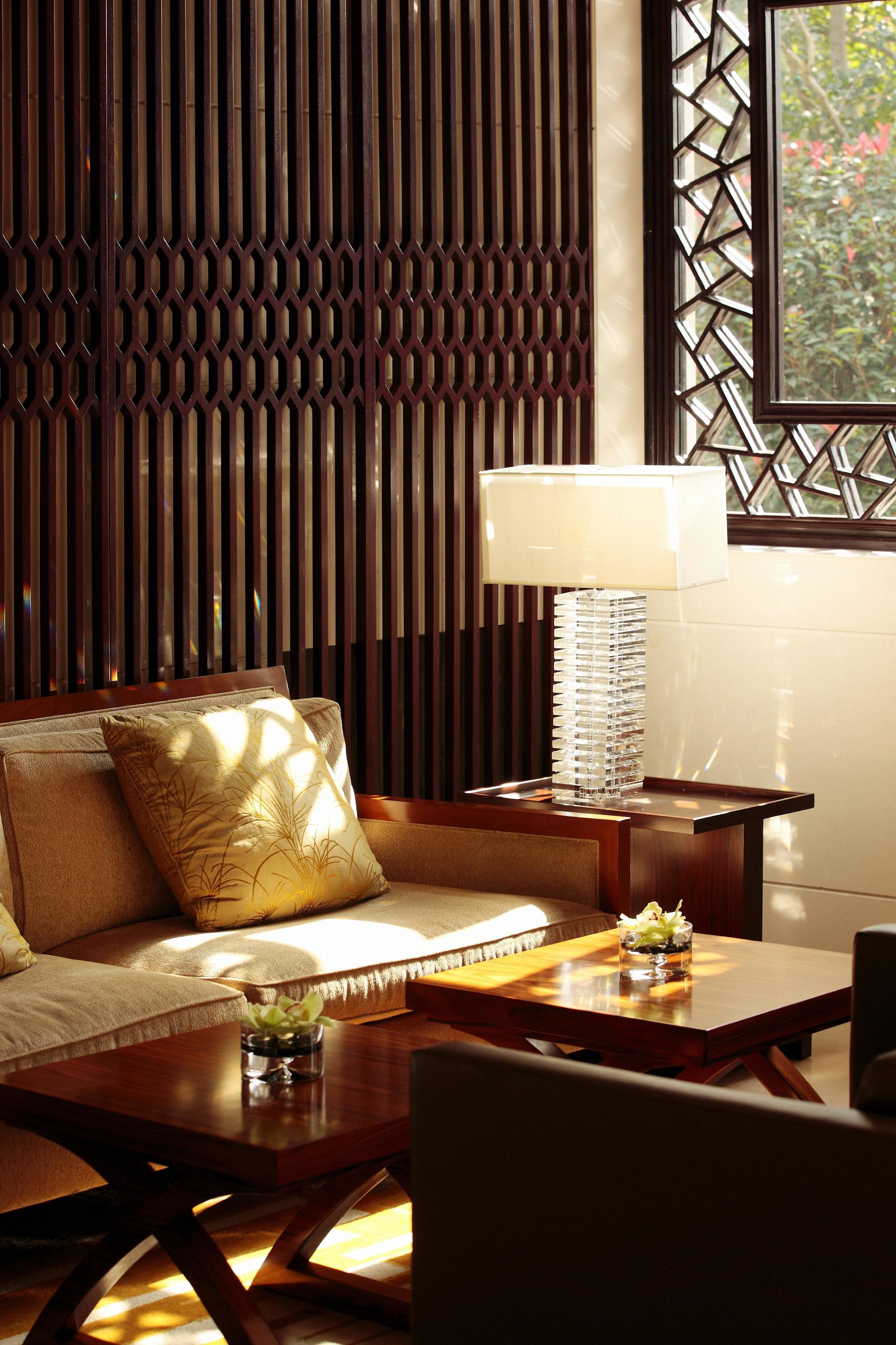 A modern room with a sofa, a wooden coffee table, a lamp, and a decorative wall panel.