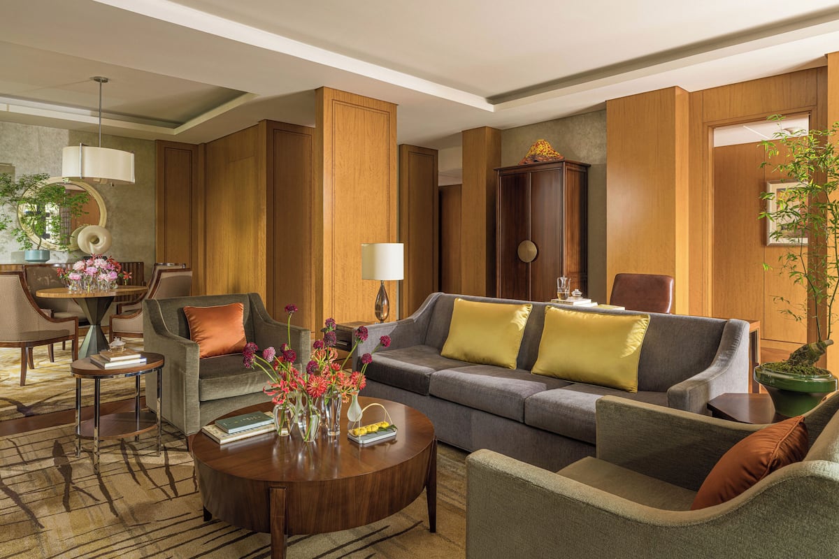 A modern living room with a sofa, armchairs, a coffee table, and a dining area with chairs and a table.