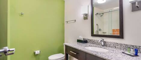 A bathroom with a green wall, a white toilet, a sink with a mirror, and a towel rack.