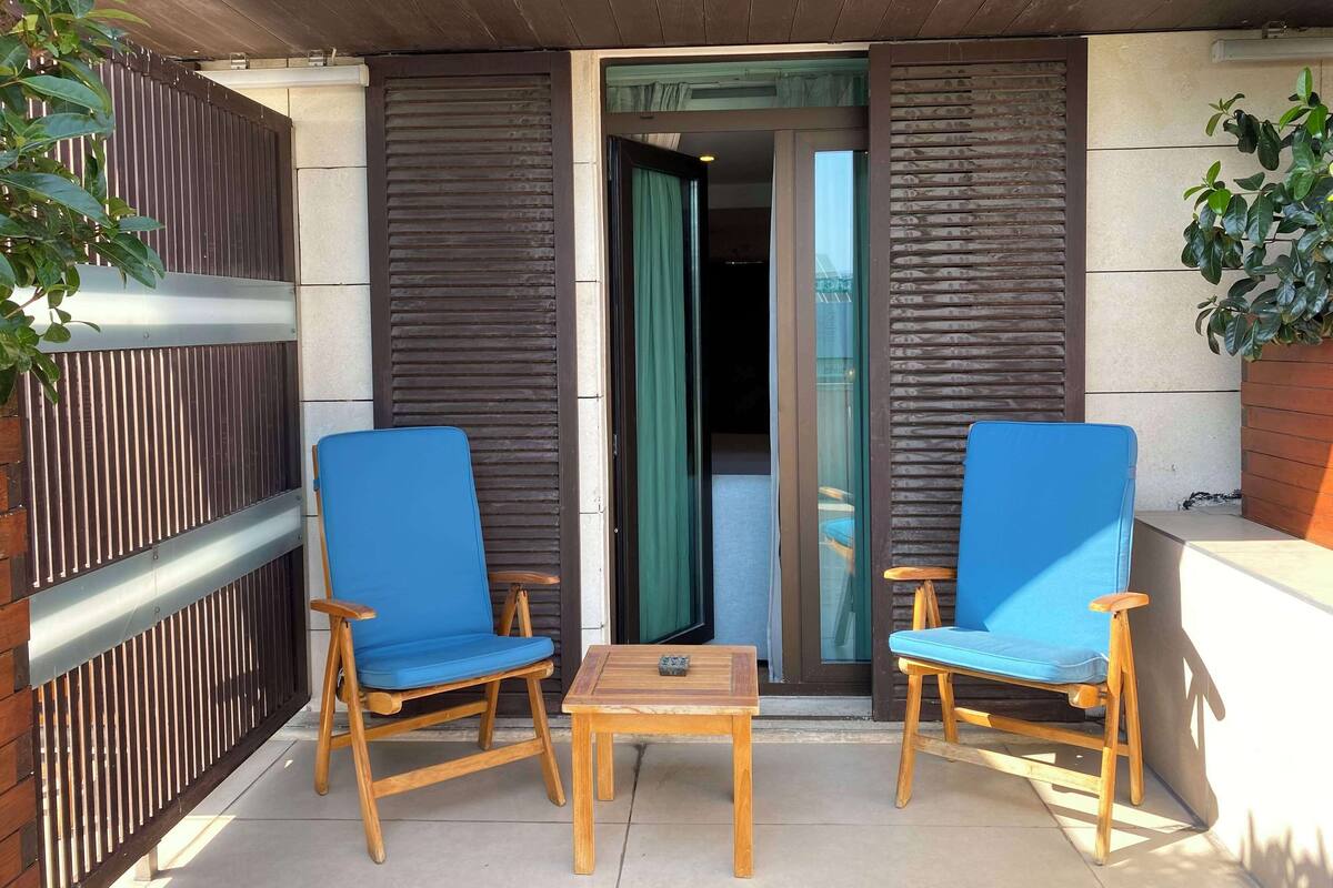 A balcony with two blue chairs and a small wooden table.