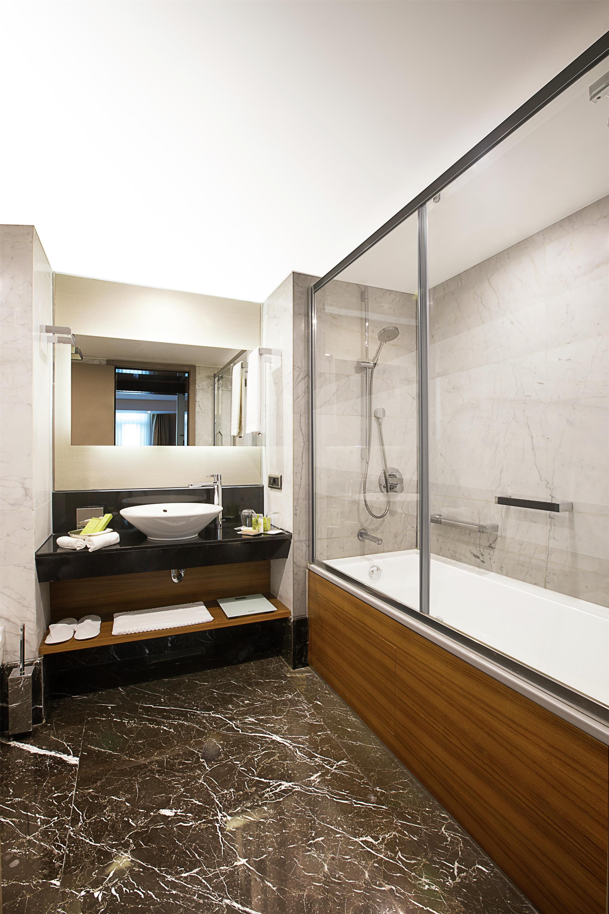 A modern bathroom with a large mirror, a bathtub, and a shower area.
