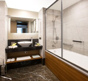 Ein modernes Badezimmer mit einer Duschkabine, einem Waschbecken mit Ablagefläche und einem Holzregal mit Handtüchern.
