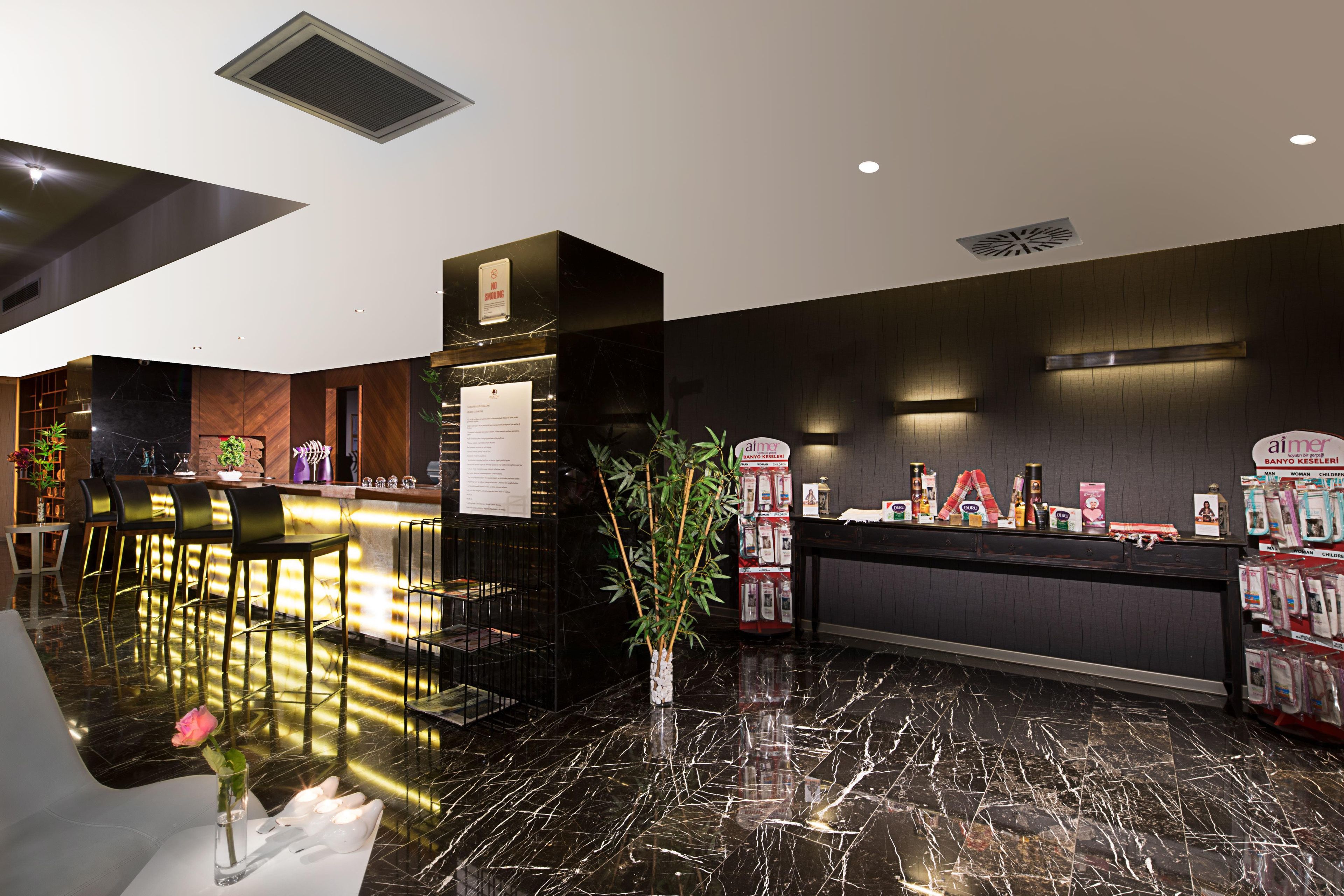 A modern hotel lobby with a marble reception desk, a no-smoking sign, and a display of toiletries.