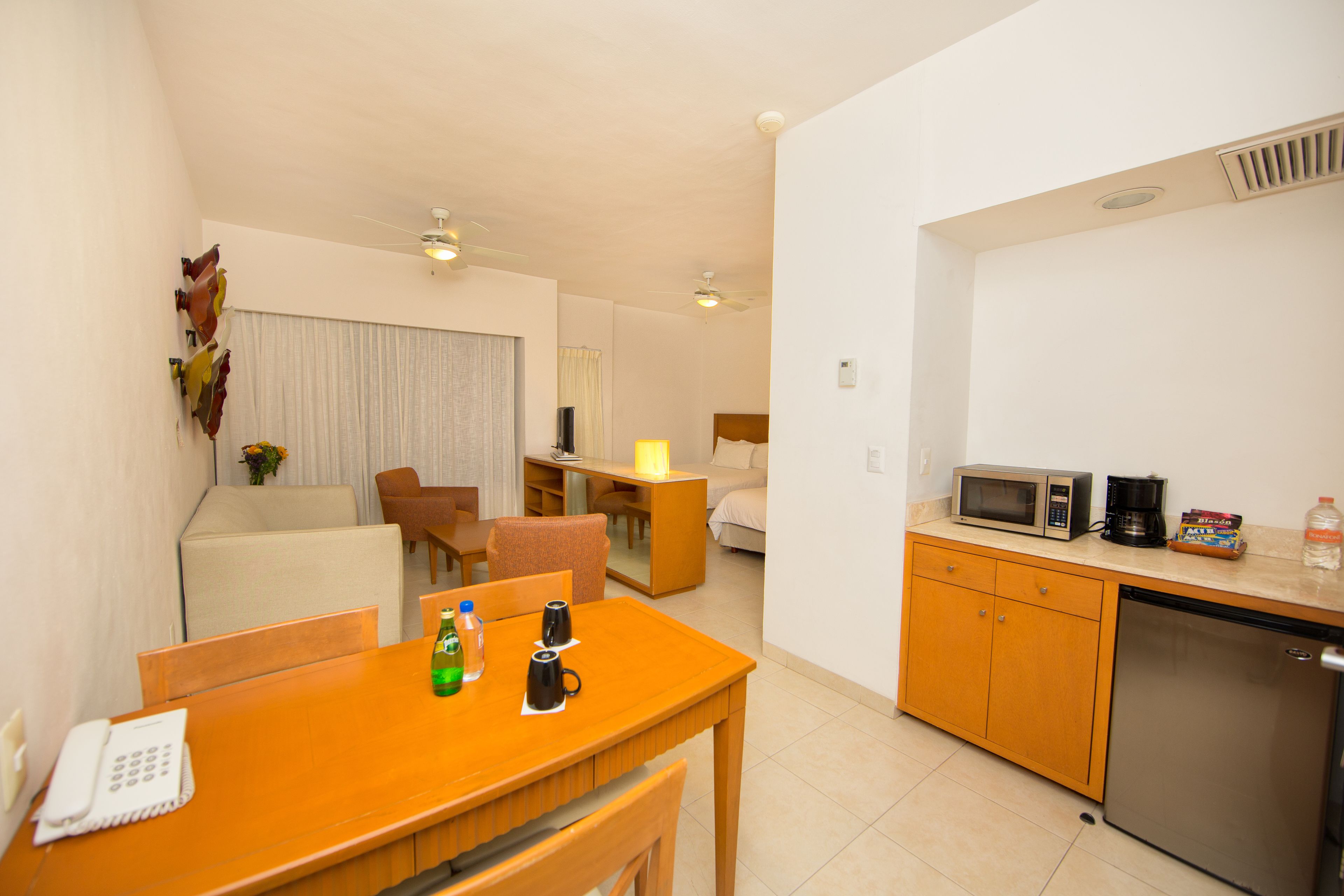 Una habitación de hotel compacta con kitchenette, comedor y sala de estar.