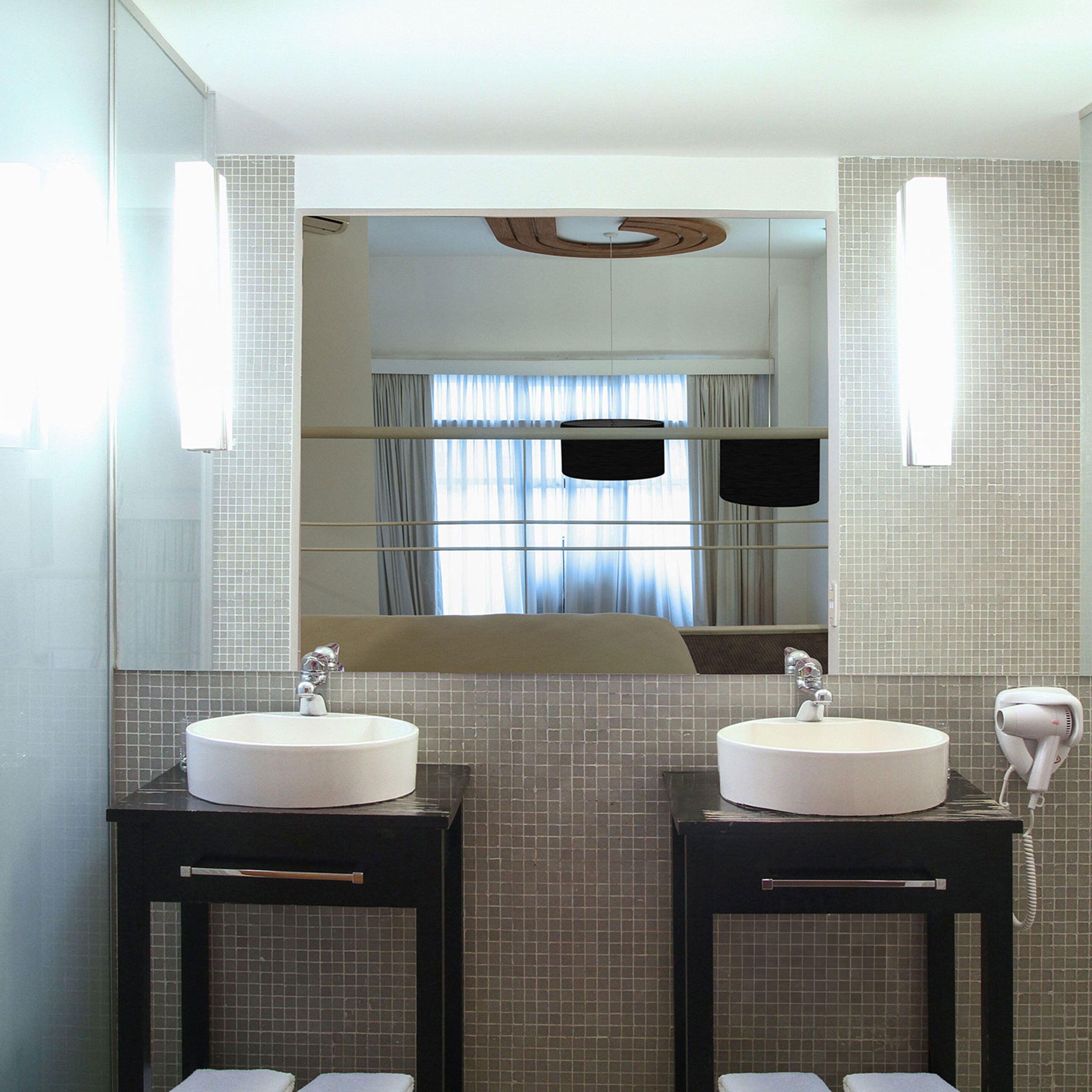 A modern bathroom with two sinks, a large mirror, and a hairdryer on the right.