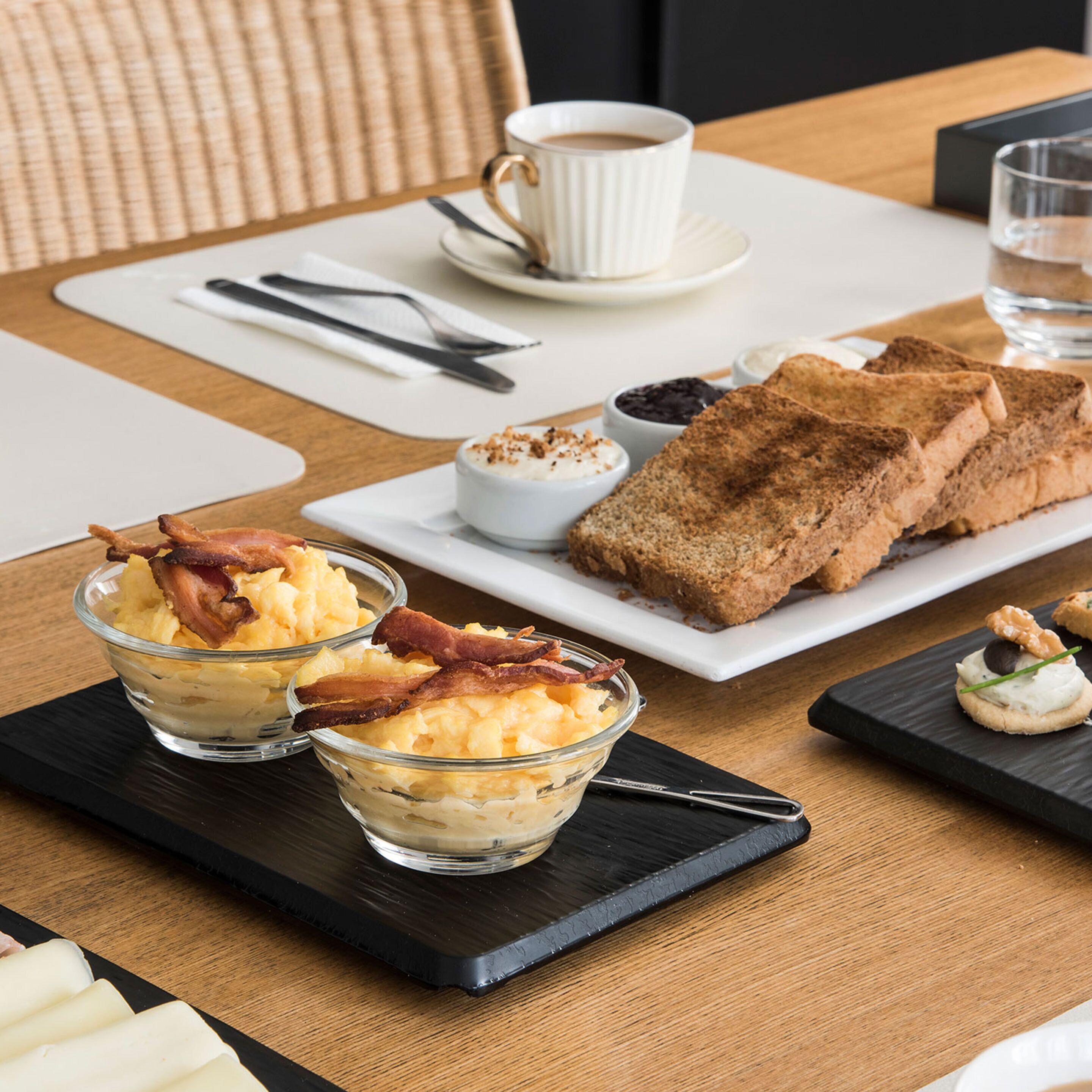 Un plateau de petit-déjeuner avec des toasts, des œufs brouillés et du bacon.