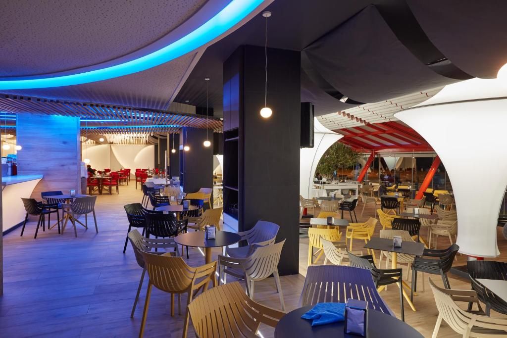 A modern indoor dining area with multiple seating arrangements, including tables and chairs, and a curved ceiling structure.