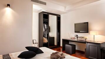 Una habitación de hotel moderna con una cama, un escritorio, un televisor y un armario.