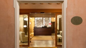 Un espace d’accueil comprenant un comptoir de réception en bois, un bureau d’accueil et un pupitre de réception avec une lampe rouge.