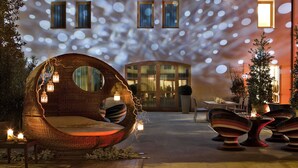 Un fauteuil suspendu de forme circulaire, doté d’un siège et d’un dossier rembourrés, et entouré de luminaires de style lanterne.