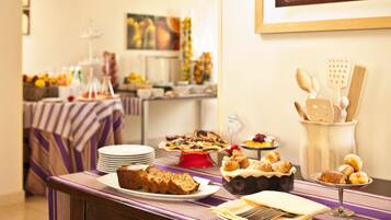 A buffet table with various food items, a framed picture on the wall, and a wooden utensil holder.