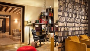 Un salon moderne avec une grande bibliothèque, un pouf rouge et un canapé jaune.