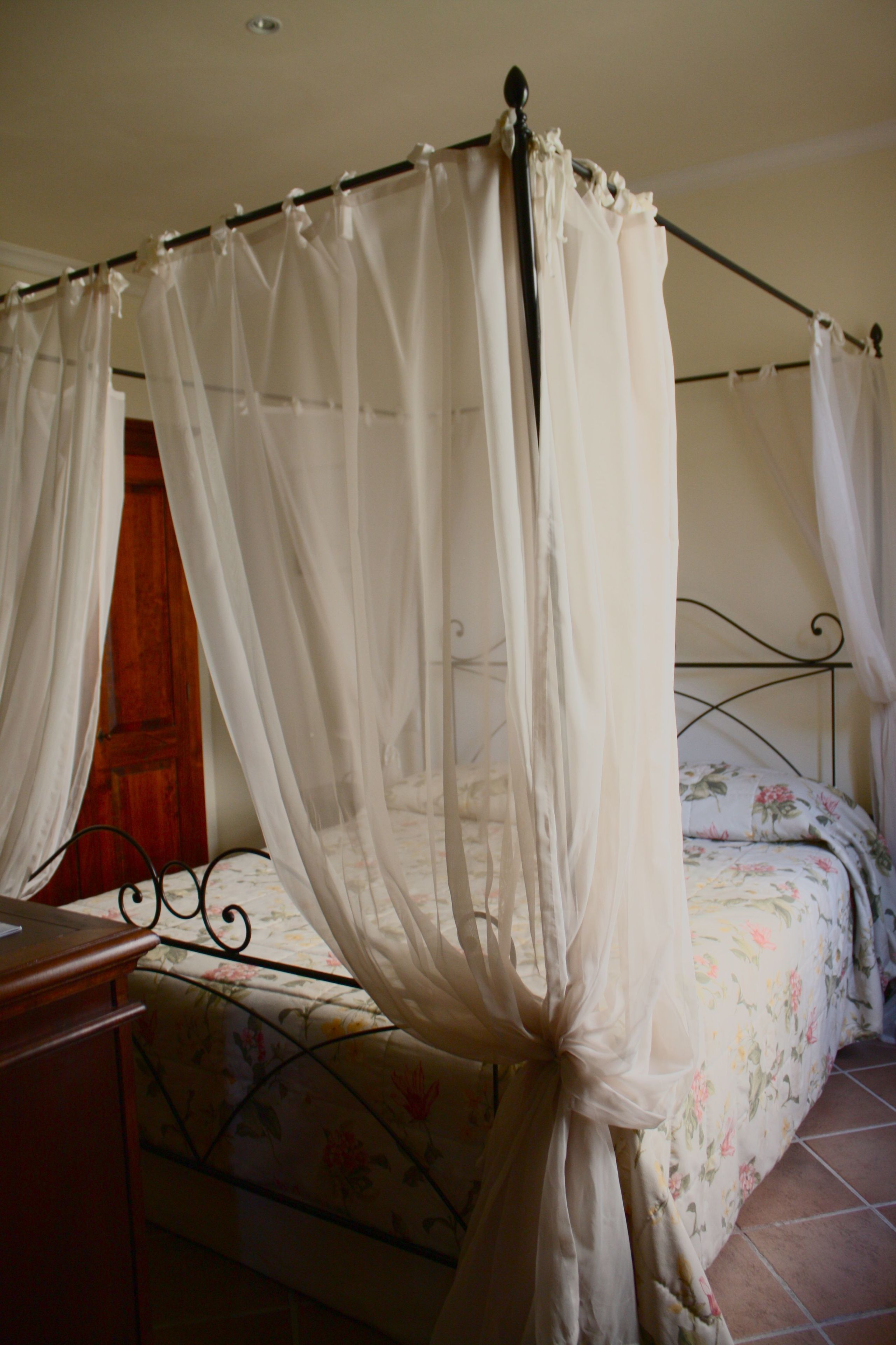 Une chambre à coucher avec un lit à baldaquin, une literie à motifs floraux et une porte en bois.