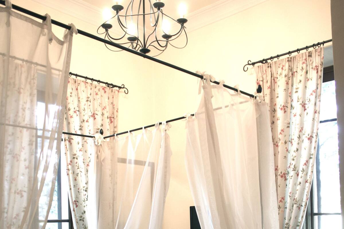 Une chambre à coucher avec un lit à baldaquin, une table de chevet avec une lampe et des rideaux à motifs floraux.