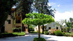 A courtyard with a central tree, surrounded by buildings with balconies and a gravel path. - Residenza Porta Guelfa (Bevagna)