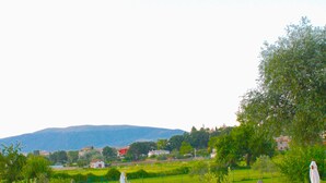 A pool area with lounge chairs and umbrellas, surrounded by greenery and a view of distant hills. - Residenza Porta Guelfa (Bevagna)