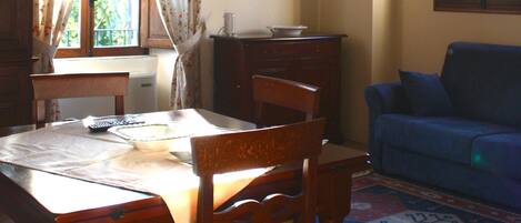 A dining area with a wooden table, chairs, and a blue sofa.