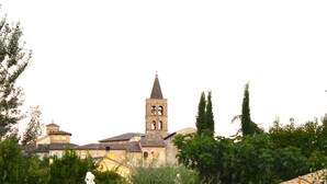 A park with outdoor seating and a distant view of a historic building with a tower. - Residenza Porta Guelfa (Bevagna)