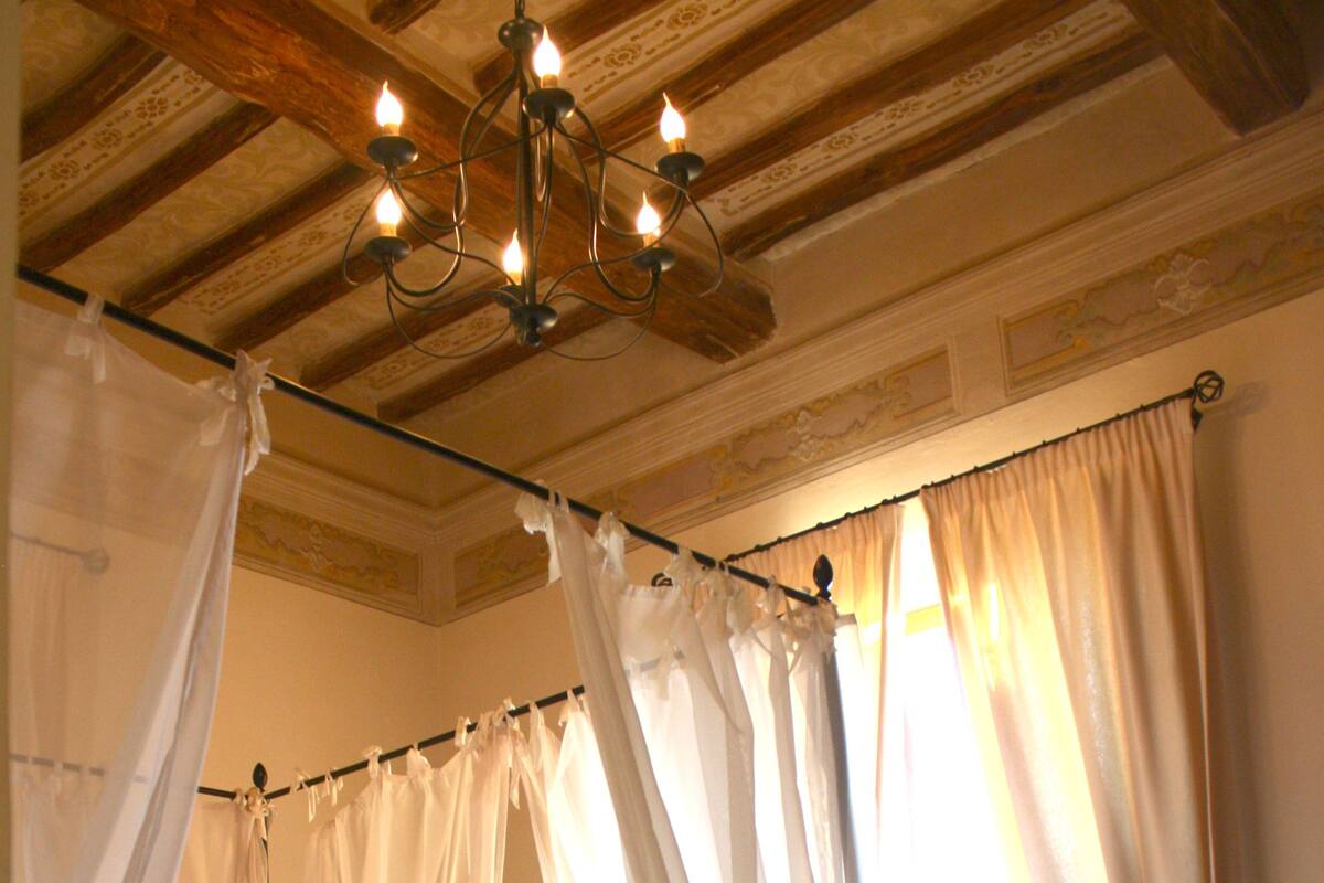 Une chambre à coucher avec un lit, un lustre et des rideaux en voile.