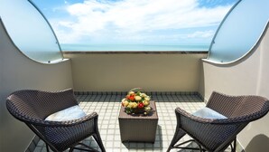 A balcony with two wicker chairs, a small table with a floral arrangement, and a view of the ocean. - Esmeralda Praia Hotel (Natal)