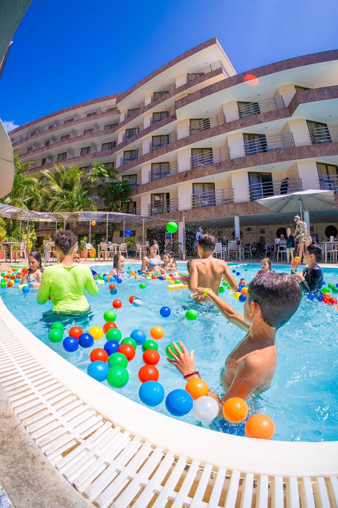 Zona de piscina con varios niveles de balcones y un cielo azul despejado.